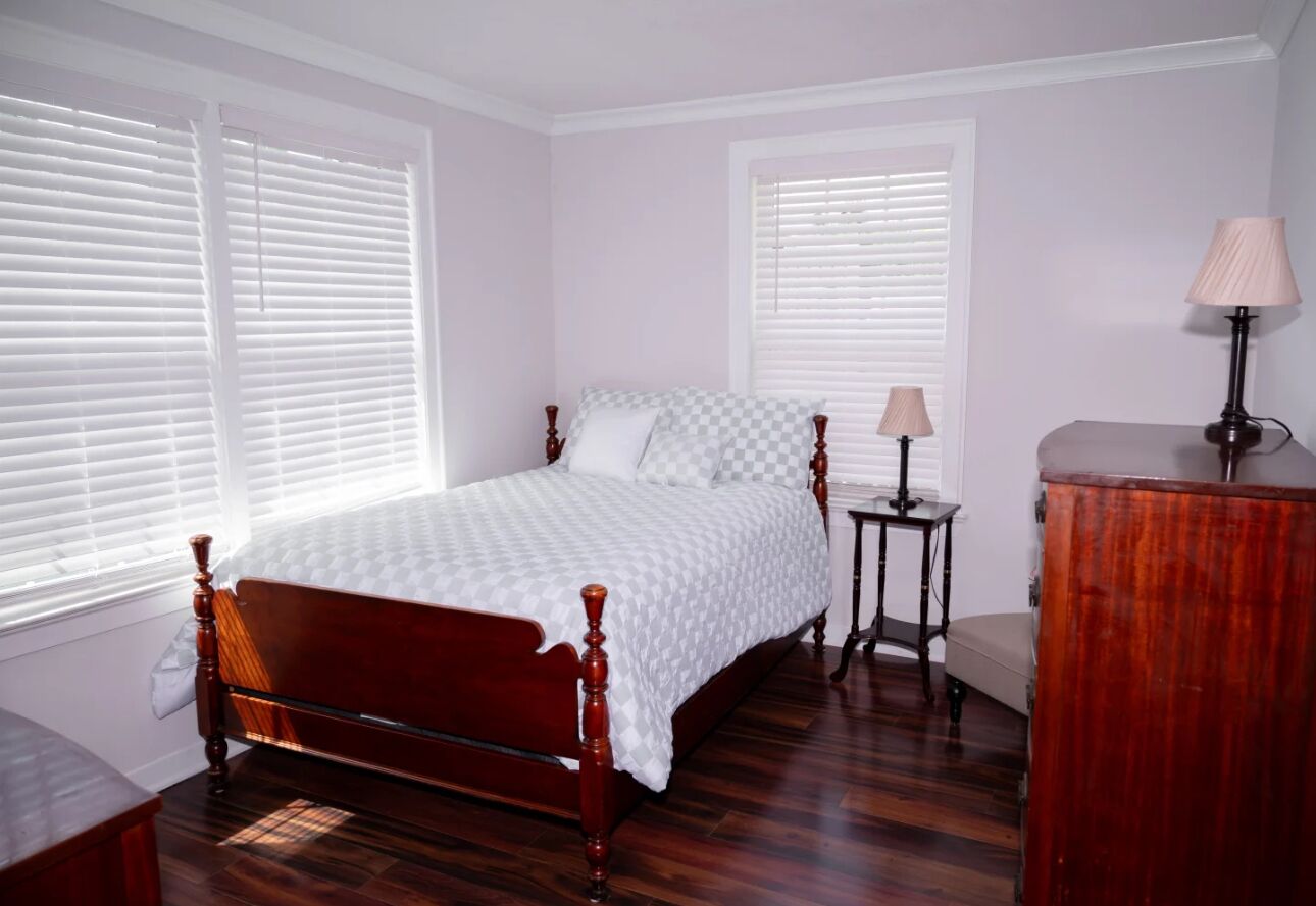 Une chambre à coucher avec un lit en bois, deux tables de chevet, une lampe et une commode.
