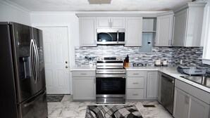 Una cocina moderna con electrodomésticos de acero inoxidable, armarios blancos y una alfombra estampada.