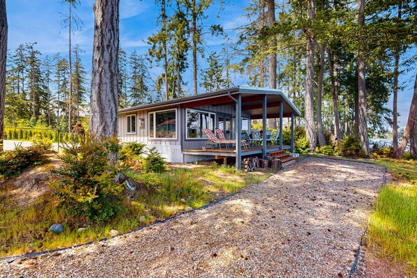 A cabin with a porch, surrounded by tall trees and a gravel path. - Family-friendly, soundfront getaway with deck, Wifi, W/D and mountain views (Fox Island)