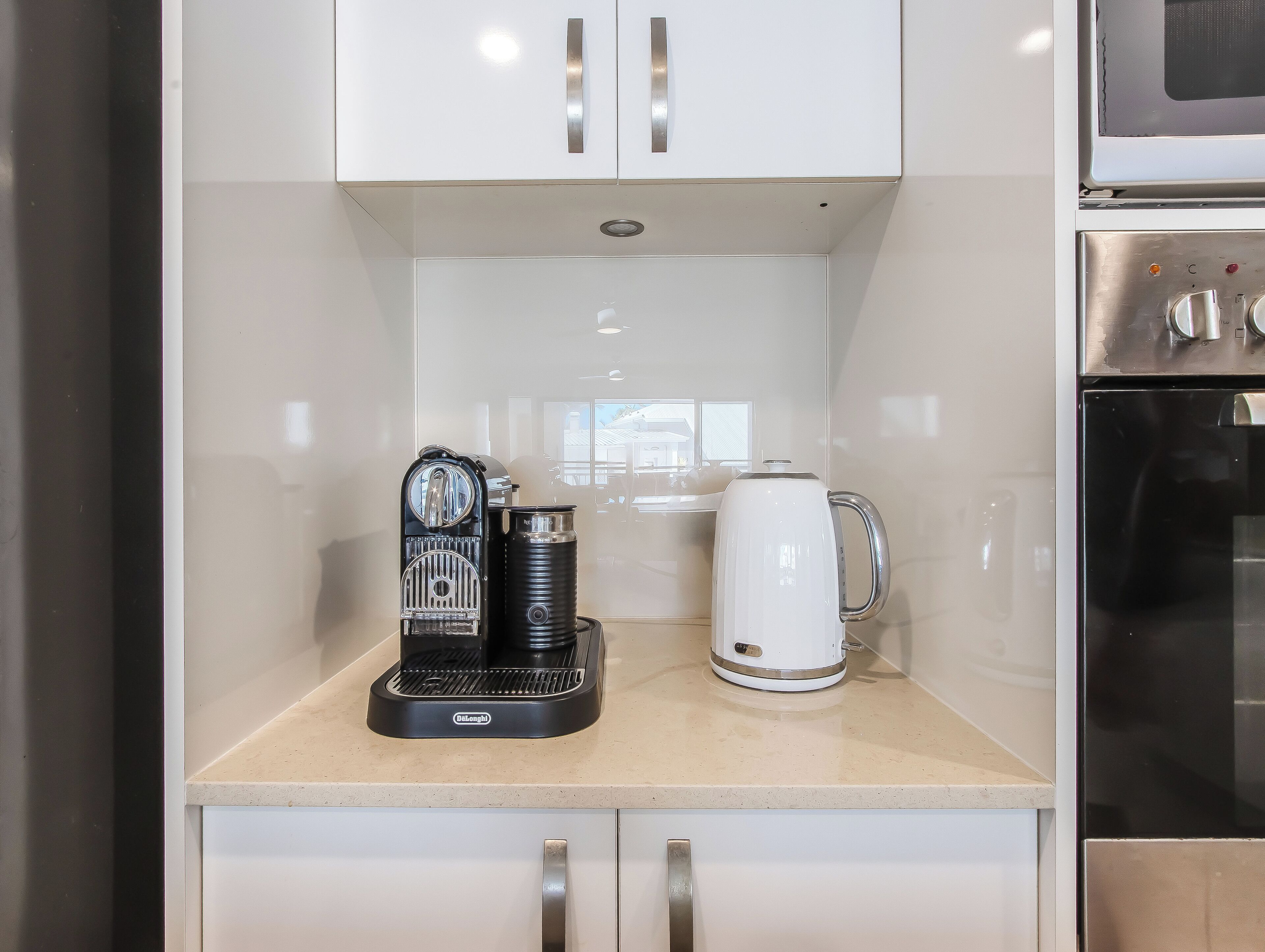 A kitchenette with a coffee maker, a kettle, and a microwave.