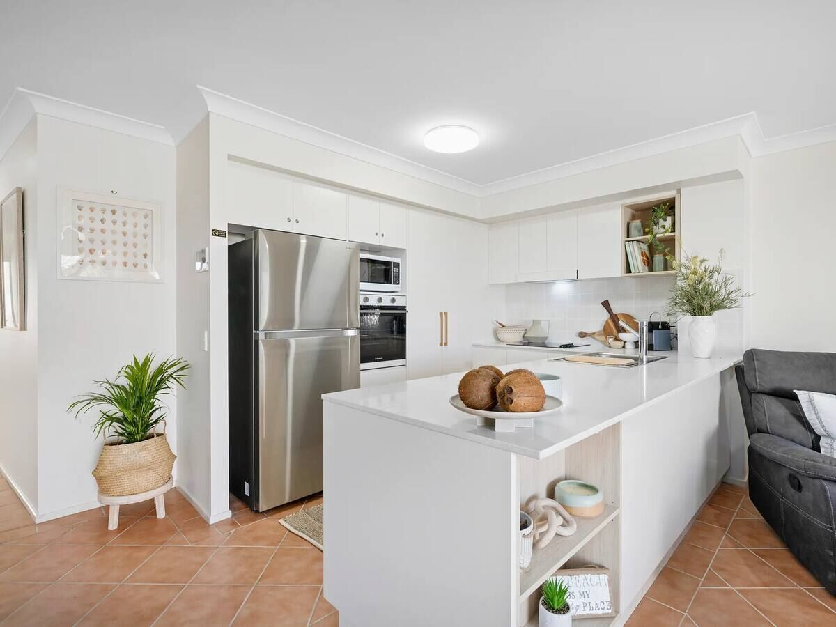 A modern kitchen with white cabinetry, stainless steel appliances, and a central island.