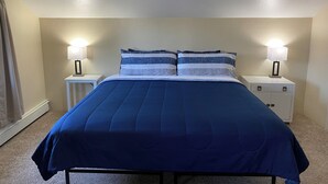 Une chambre à coucher avec un lit, deux tables de chevet avec des lampes et une fenêtre avec des rideaux.