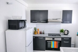 Una cocina moderna con refrigerador, microondas, estufa, horno y gabinetes negros.