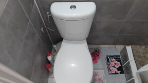 Des toilettes blanches dans une salle de bain carrelée de carreaux gris.