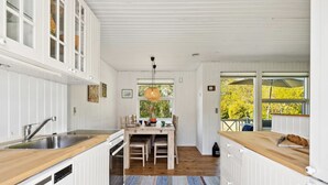 A kitchen with white cabinetry, a wooden countertop, and a dining area with a table and chairs. - "Aldina" - 400m to the fjord by Interhome (Havndal)