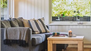 A cozy living room with a grey sofa, striped pillows, a wooden coffee table, and a window with a view of greenery. - "Aldina" - 400m to the fjord by Interhome (Havndal)