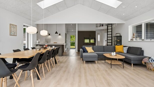 Un amplio salón con mesa de comedor, sofás y una cocina al fondo.