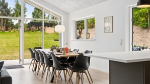 Una cocina moderna con una isla grande, sillas negras y vistas al jardín.
