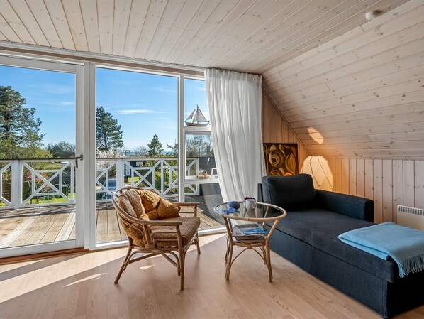 A cozy room with a sofa, a chair, a table, and a view of the outdoors.