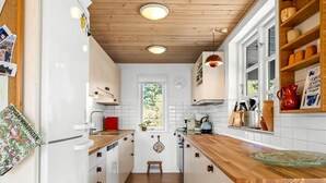 A kitchen with wooden cabinets, a white refrigerator, and a window with a view.