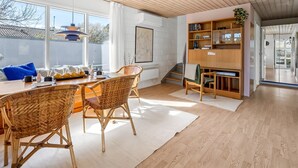 A modern interior with a dining area, wooden ceiling, and a bookshelf.