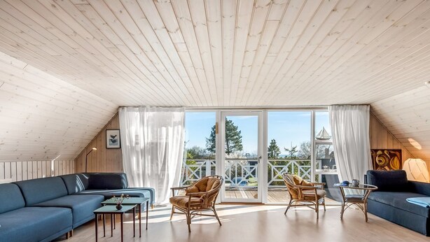 A spacious loft with a high ceiling, a large sliding glass door leading to a deck, and a blue sofa set.