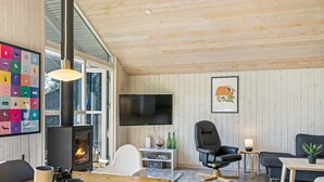 A cozy living room with a fireplace, a TV mounted on the wall, and a dining area with a wooden table and chairs.