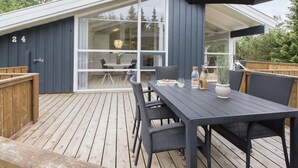 A modern outdoor patio with a wooden deck, a dining table with chairs, and a large umbrella. - "Ingwin" -  from the sea by Interhome (Hals)