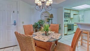 A dining area with wicker chairs, a round table, and a chandelier. - Fully renovated in 2025!! (Saint Simons Island)