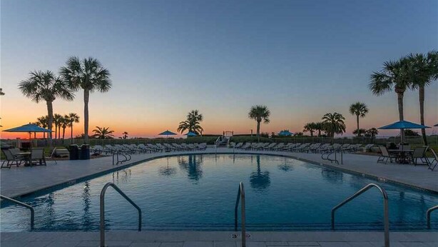 A swimming pool with lounge chairs and umbrellas, surrounded by palm trees. - Fully renovated in 2025!! (Saint Simons Island)