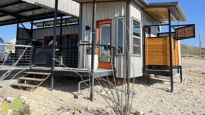 Un bâtiment moderne avec une façade en métal, une porte en bois et un espace d’entrée abrité.