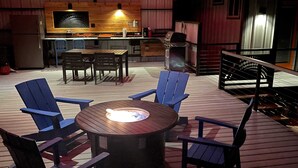 Une terrasse extérieure avec une table ronde et des chaises, un barbecue et un coin bar.