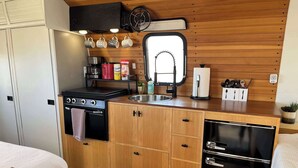 Une petite cuisine équipée avec une cuisinière, un four, un évier et un réfrigérateur.