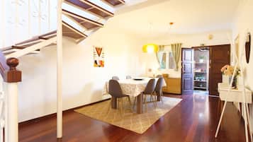 A dining area with a table, chairs, and a staircase.