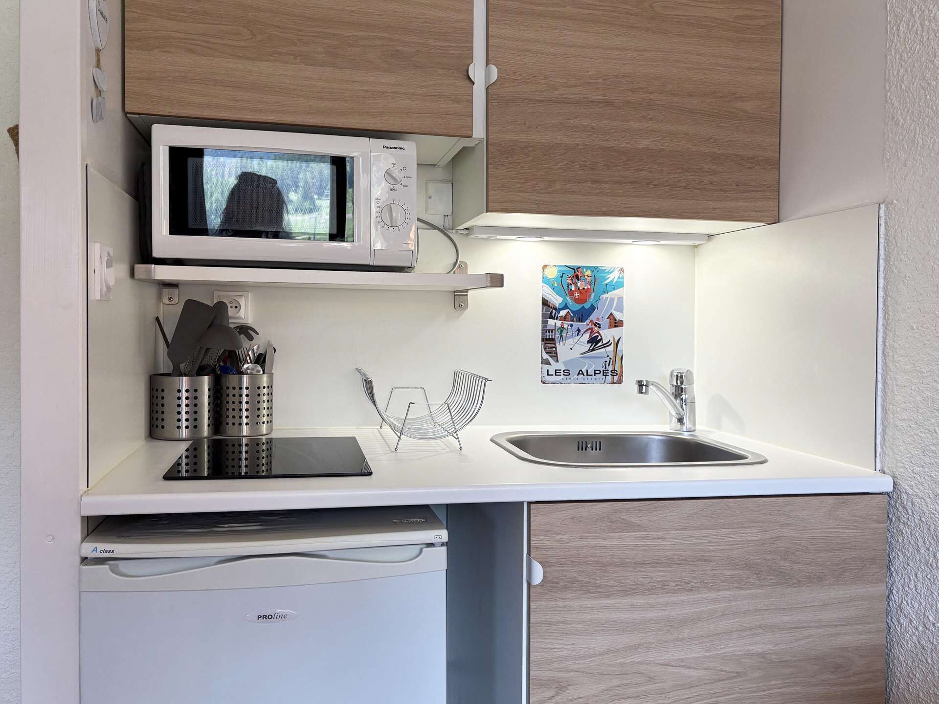 Cocina compacta con microondas, pileta y heladera pequeña.