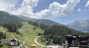 A mountainous landscape with a ski resort, including a ski lift, buildings, and a clear sky.