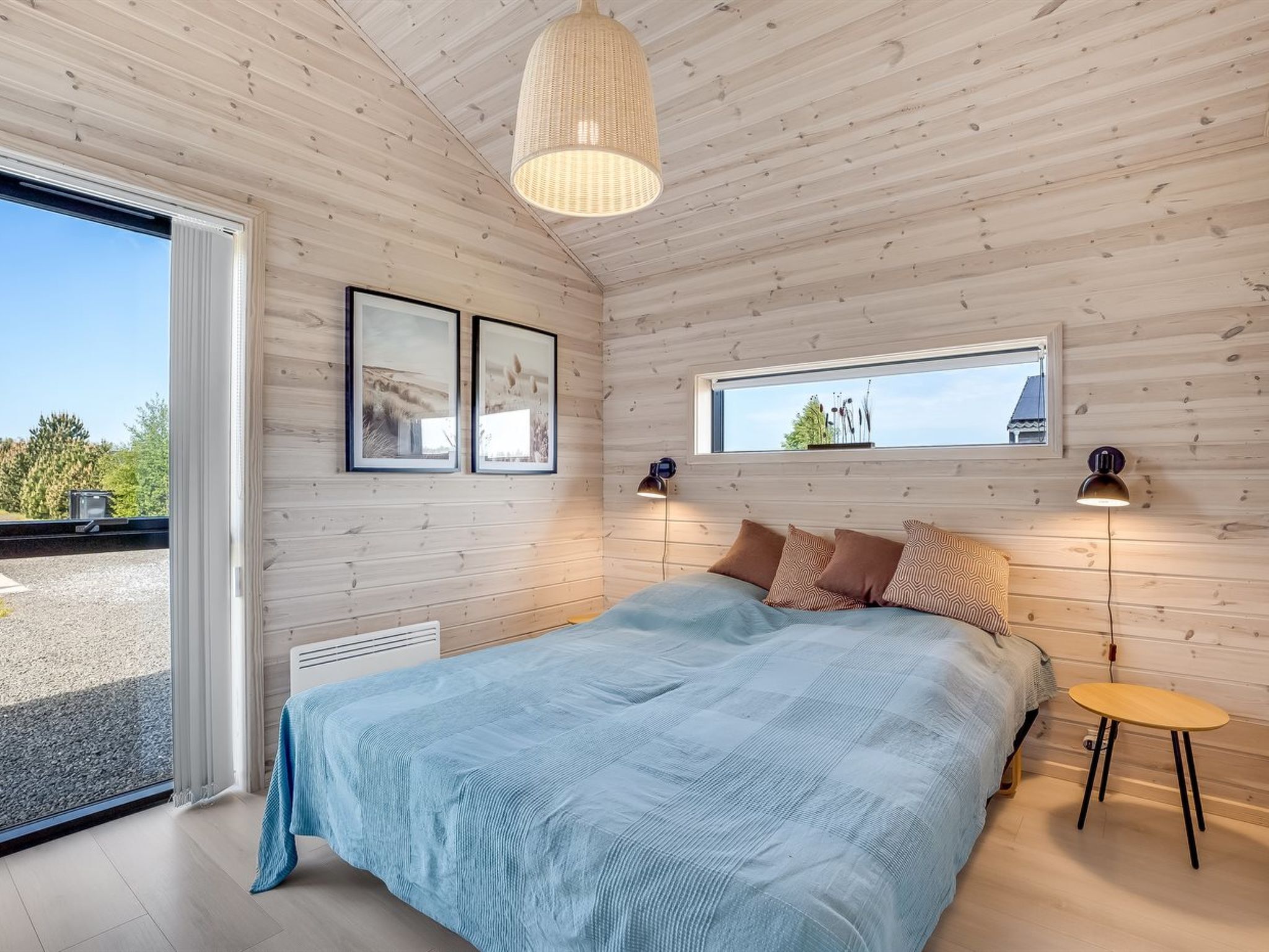 Une chambre moderne avec un grand lit, des murs en bois, une fenêtre et deux lampes fixées au mur.