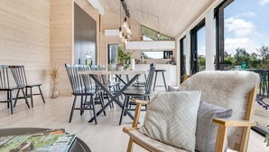 Ein modernes Interieur mit Essbereich, einer gemütlichen Sitzecke und einer durch eine offene Tür einsehbarer Küche.