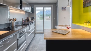 Una cocina moderna con una isla grande, electrodomésticos de acero inoxidable y vistas de la ciudad a través de la puerta de vidrio.