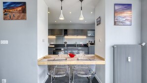 Una cocina moderna con una isla central, iluminación colgante y obras de arte en las paredes.