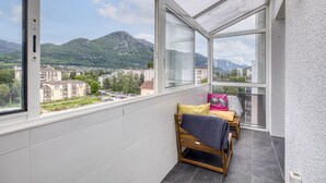 Un balcón con una cama y vistas a montañas y a la ciudad.