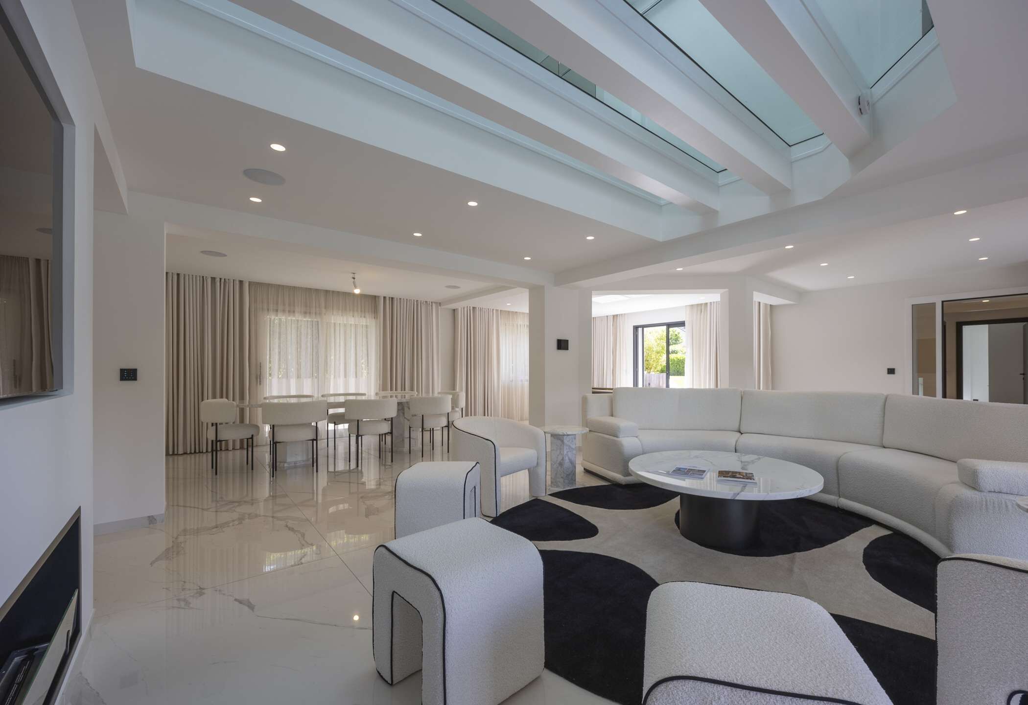 Un salon spacieux au design moderne, comprenant un grand canapé, une table basse et un coin repas avec des chaises et une table.