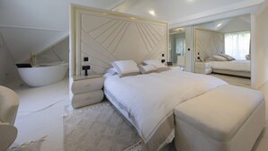 Une chambre à coucher moderne avec un grand lit, une baignoire intégrée et un grand miroir.