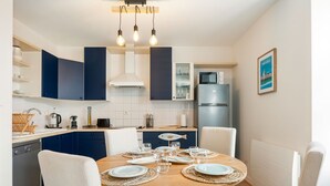 Une cuisine moderne avec des meubles bleu foncé, un plan de travail blanc et un four à micro-ondes encastré.