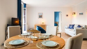 Un coin repas avec une table ronde en bois, dressée pour quatre personnes, entourée de chaises.