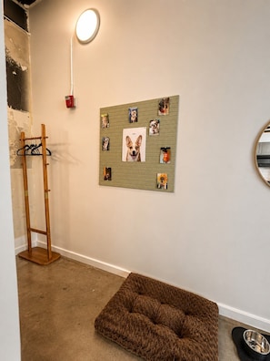 Ein Zimmer mit Hundebett, Wandcollage, Kleiderständer und Stehlampe.