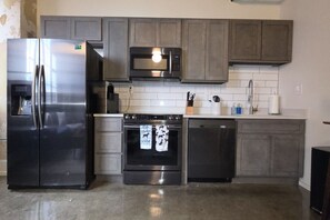A kitchen with a stainless steel refrigerator, a microwave, an oven, and a dishwasher.