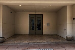 A building entrance with a double door, a wall-mounted intercom, and two large planters. - Old City Loft | Gay St | Pets | Near Neyland (Knoxville)