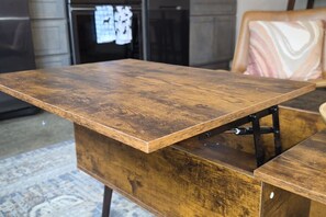 A wooden table with a metal support structure, a patterned rug, and a chair with a cushion. - Old City Loft | Gay St | Pets | Near Neyland (Knoxville)