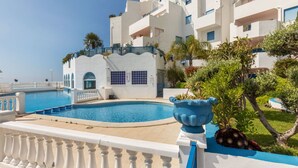 A modern hotel with a swimming pool, white and blue exterior, and lush greenery. - Perla Blanca by Interhome (Peñiscola)