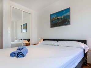 Ein Hotelzimmer mit Bett, einem Leuchtturm-Gemälde und einem Spiegel, der den Raum widerspiegelt.
