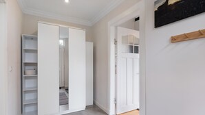 Un pasillo con un armario blanco, una puerta de madera y un estante con una cesta.