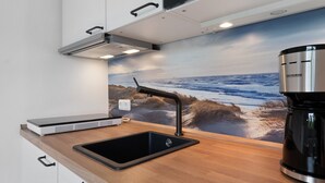 Una cocina moderna con cafetera integrada, una tableta y un lavamanos.