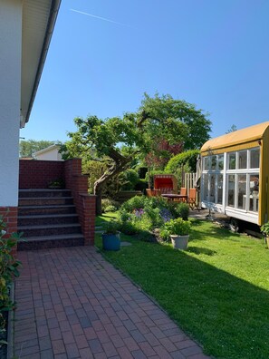 Un chemin pavé de briques mène à une maison devant laquelle est garé un autobus jaune dans la cour.
