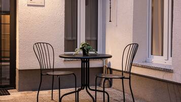 A small outdoor seating area with two metal chairs and a round table, featuring a potted plant.