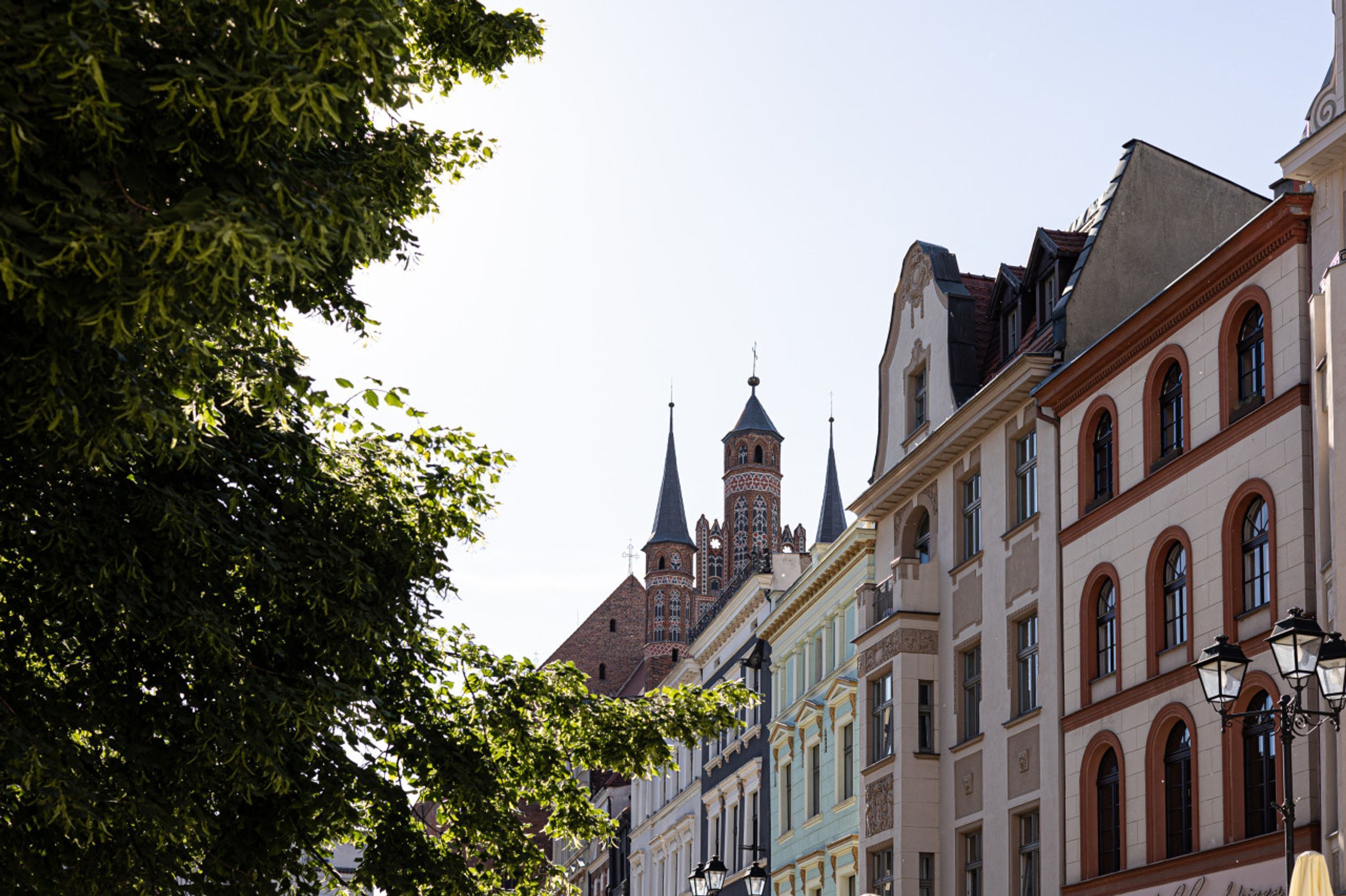 A historic building with a tower and spires, surrounded by trees and other buildings.