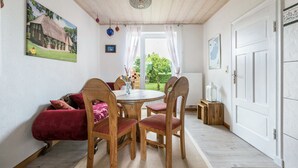 Ein Essbereich mit einem Holztisch und Stühlen, einem roten Sofa und einem Hausbild an der Wand.