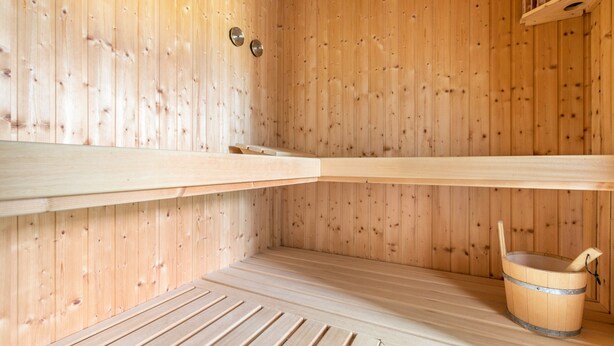 Eine Holzsauna mit Bänken und einem Eimer.