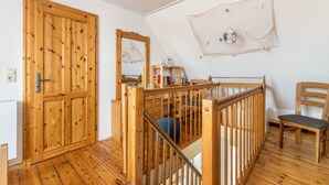 Eine Holztür, ein Holzstuhl, ein Holllaufgeländer und ein an der Wand befestigter Spiegel.