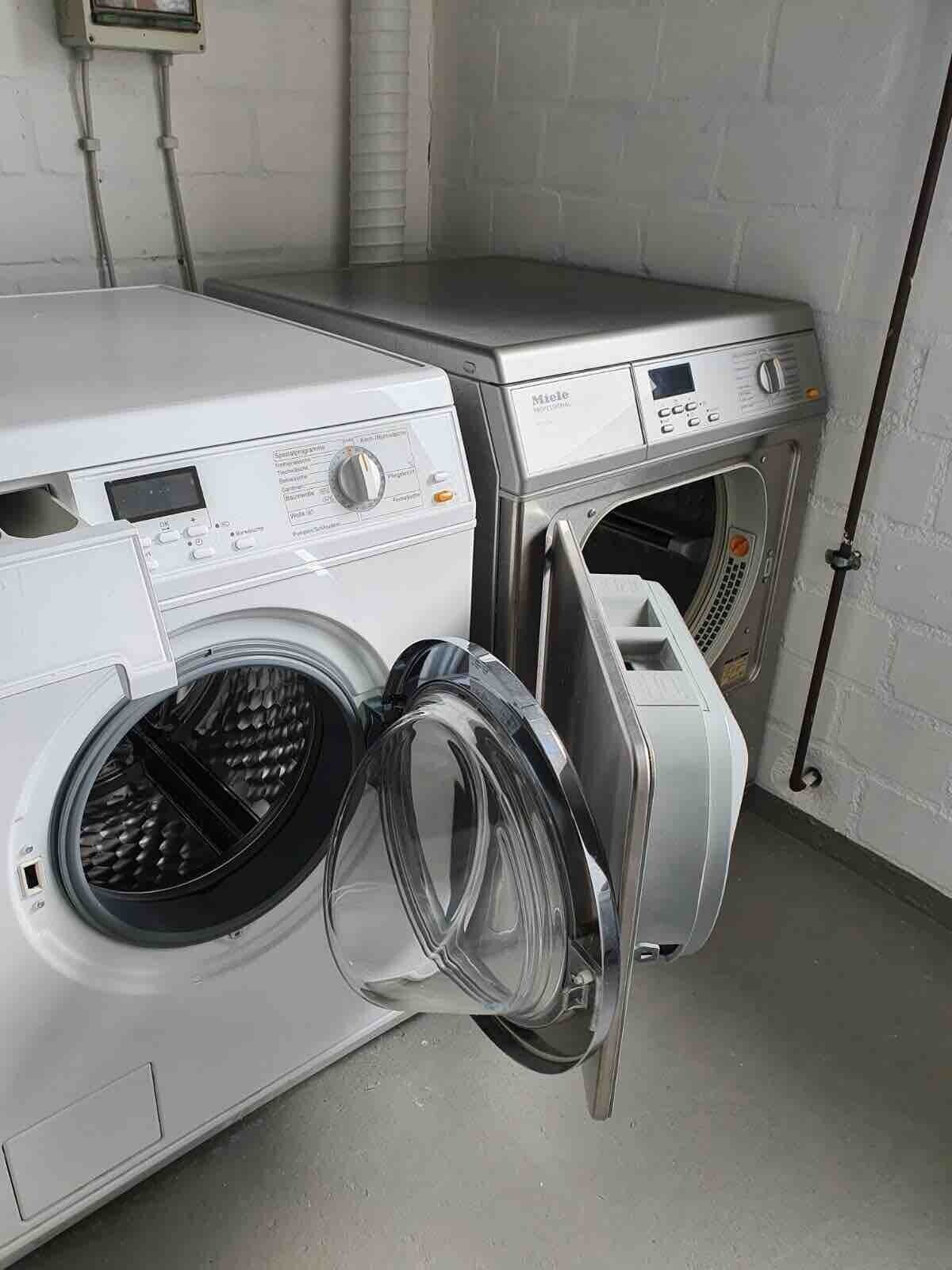 A laundry room with two washing machines, one with its door open.